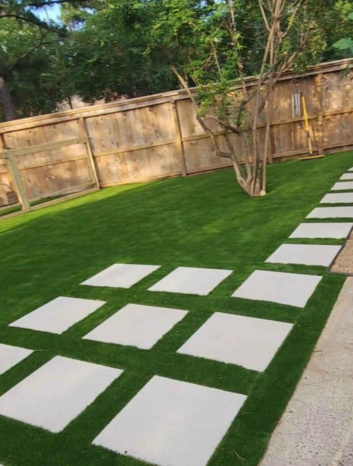 Concrete pavers laid in a checkerboard pattern through turf in a fenced backyard